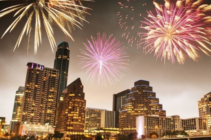 Colorful fireworks over a city skyline with tall buildings at night.