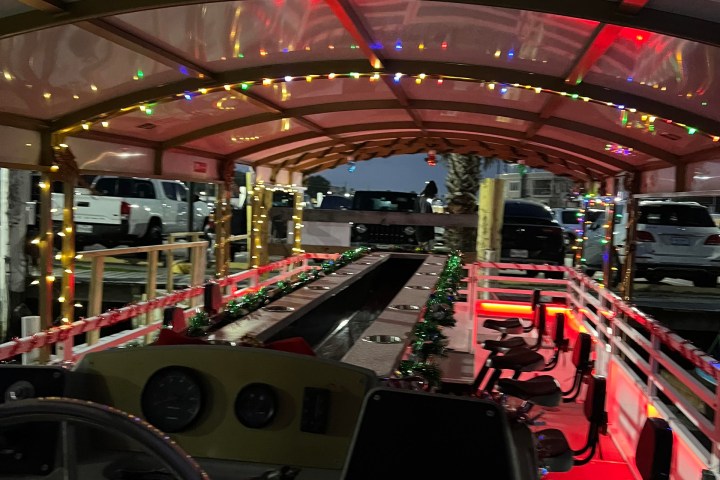 Interior of a trolley decorated with colorful string lights and empty rows of seats at night.