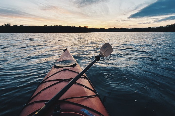 Kayak on a lake during sunset with calm water and cloudy sky.