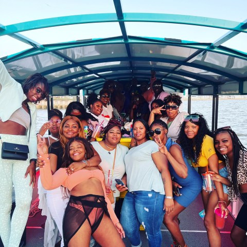Group of people smiling and posing for a photo on a boat under a canopy.