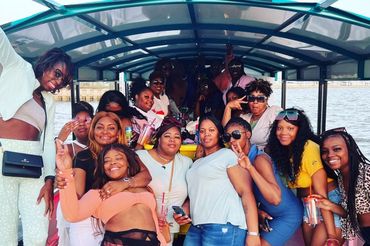Group of people smiling and posing for a photo on a boat under a canopy.